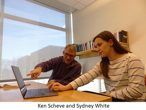 Ken Scheve and Sydney White speak at a table in an office